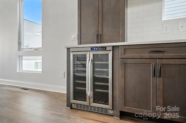 945 Westbrook Dr Unit A, Charlotte, NC 28202 - detailed view of beverage cooler, dark brown cabinetry, light wood-style flooring, light countertops, and backsplash