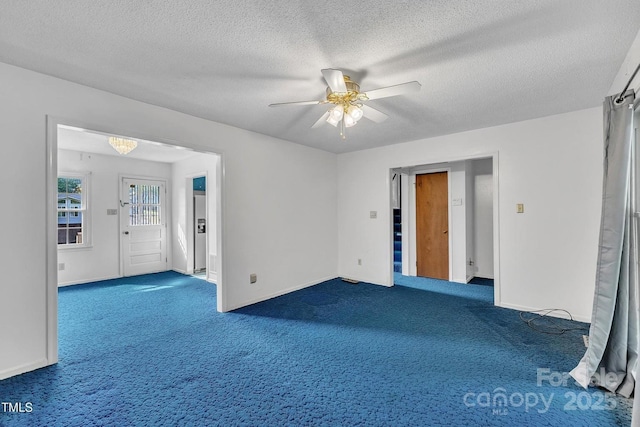 spare room with a textured ceiling, carpet flooring, baseboards, and a ceiling fan