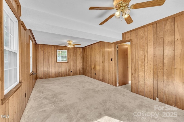 spare room with carpet, wooden walls, and a ceiling fan
