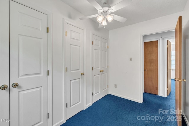 unfurnished bedroom featuring ceiling fan, dark colored carpet, and baseboards