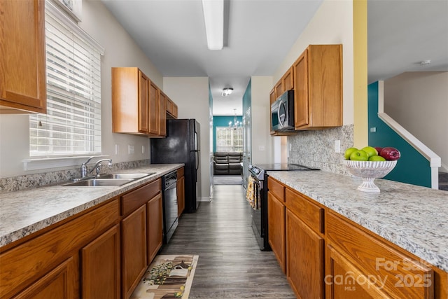kitchen featuring black appliances, a sink, light countertops, and brown cabinets