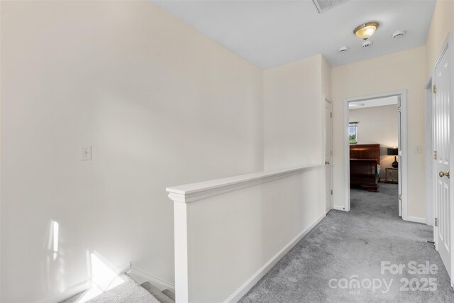 hallway with carpet, baseboards, and an upstairs landing