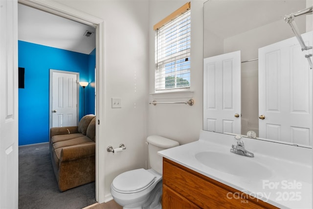 ensuite bathroom with toilet, vanity, and baseboards
