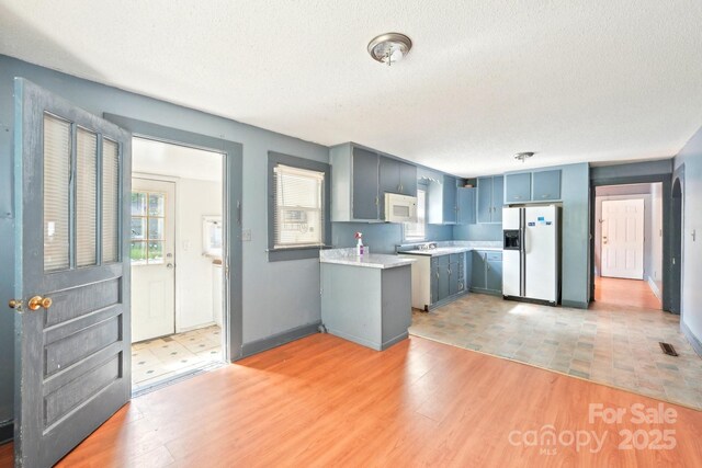409 Rosemont Ave, Kannapolis, NC 28081 - kitchen with a textured ceiling, visible vents, white appliances, light countertops, and blue cabinetry