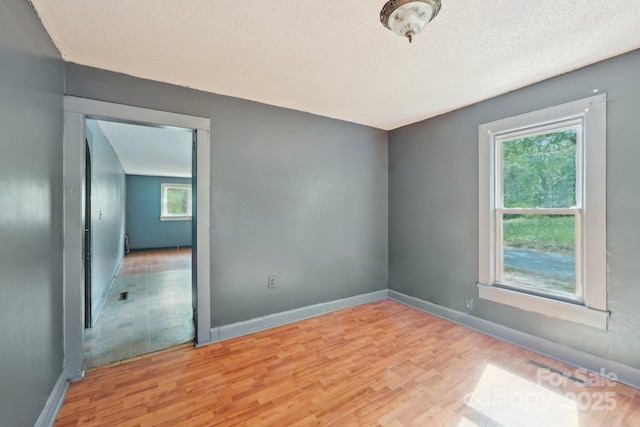 409 Rosemont Ave, Kannapolis, NC 28081 - empty room with a textured ceiling, a wealth of natural light, baseboards, and light wood-type flooring