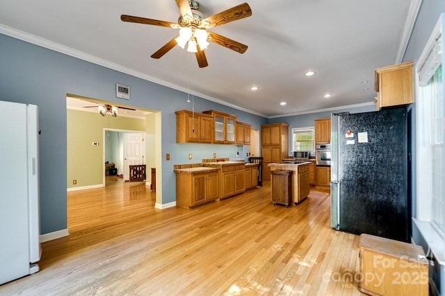 910 Hannah Mountain Rd, Otto, NC 28763 - kitchen with brown cabinetry, ornamental molding, ceiling fan, light wood-style floors, and stainless steel appliances