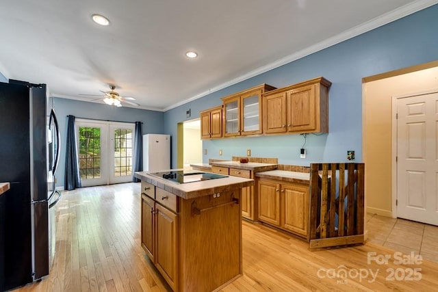 910 Hannah Mountain Rd, Otto, NC 28763 - kitchen with brown cabinetry, freestanding refrigerator, a center island, a ceiling fan, and black electric cooktop
