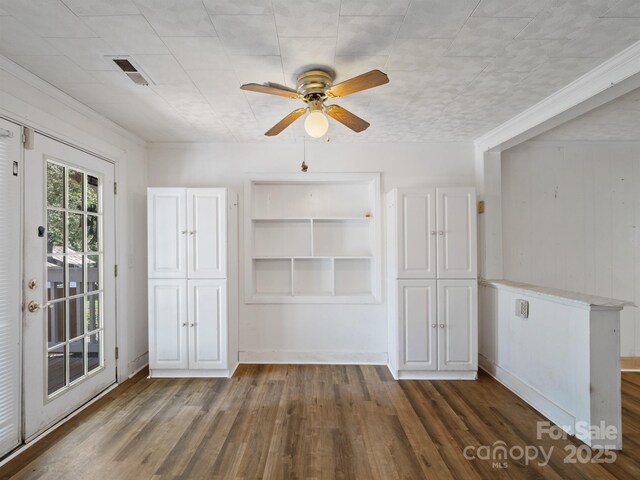 unfurnished dining area with a ceiling fan, wood finished floors, and built in features