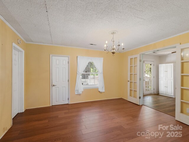 unfurnished room with ornamental molding, hardwood / wood-style flooring, a chandelier, french doors, and a textured ceiling