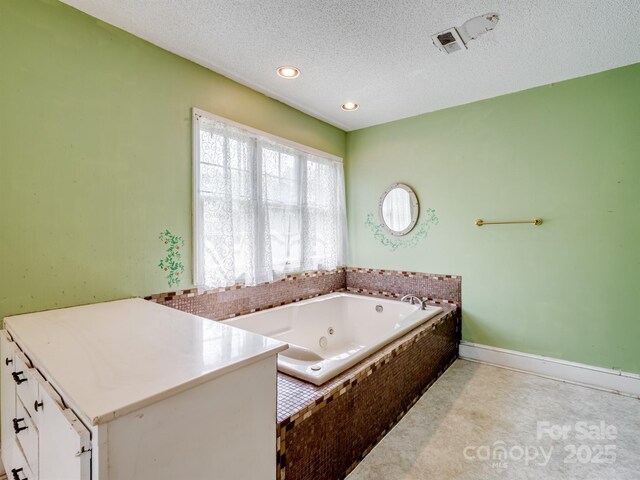 bathroom featuring a textured ceiling, a whirlpool tub, and recessed lighting
