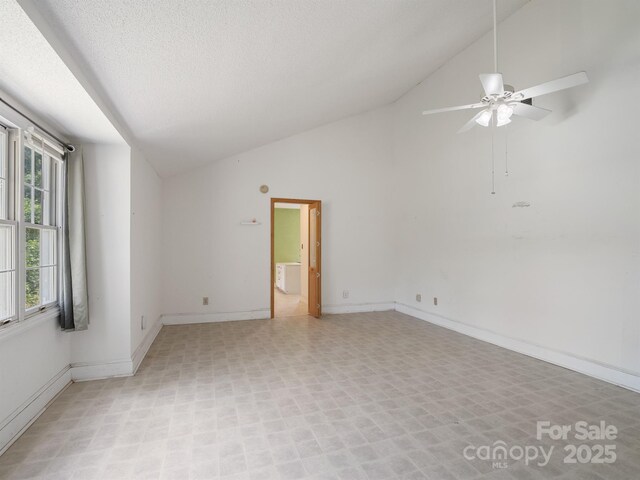 empty room with a ceiling fan, light floors, baseboards, high vaulted ceiling, and a textured ceiling