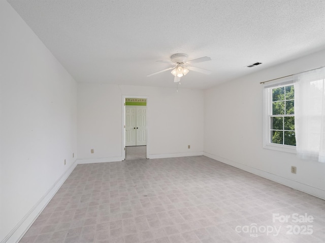 unfurnished room featuring ceiling fan, baseboards, and a textured ceiling