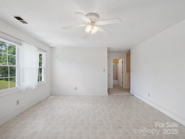 unfurnished room featuring ceiling fan, baseboards, and a textured ceiling