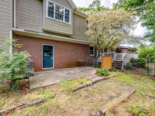 rear view of house with brick siding, a deck, a patio area, and fence