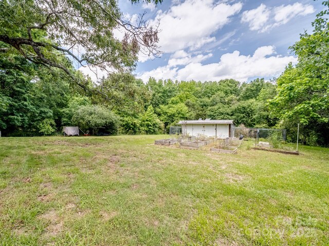 view of green lawn with a garden and a wooded view