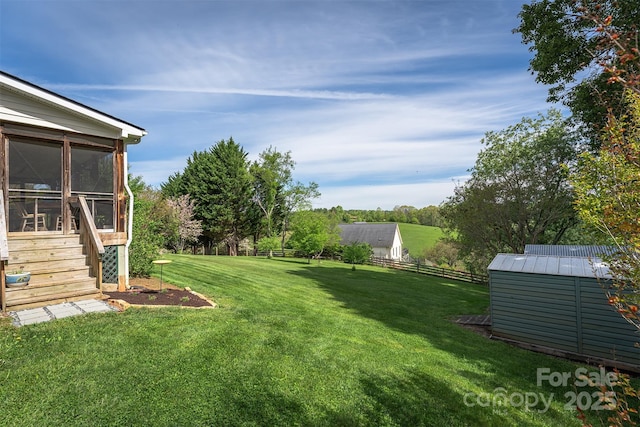 view of yard featuring an outdoor structure, a sunroom, fence, and a storage unit