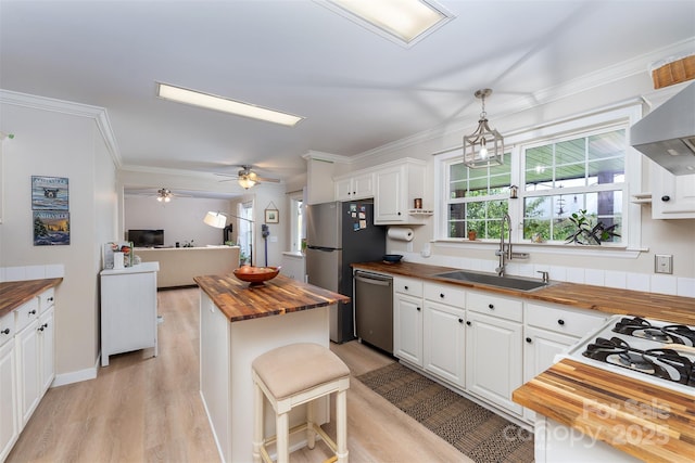 kitchen featuring a sink, stainless steel appliances, wood counters, light wood-style flooring, and white cabinetry