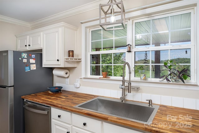 kitchen featuring a sink, stainless steel appliances, white cabinets, crown molding, and butcher block countertops