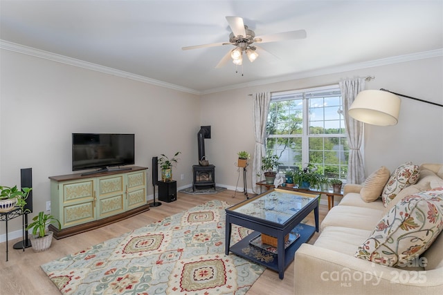 living room with a wood stove, wood finished floors, baseboards, and ornamental molding