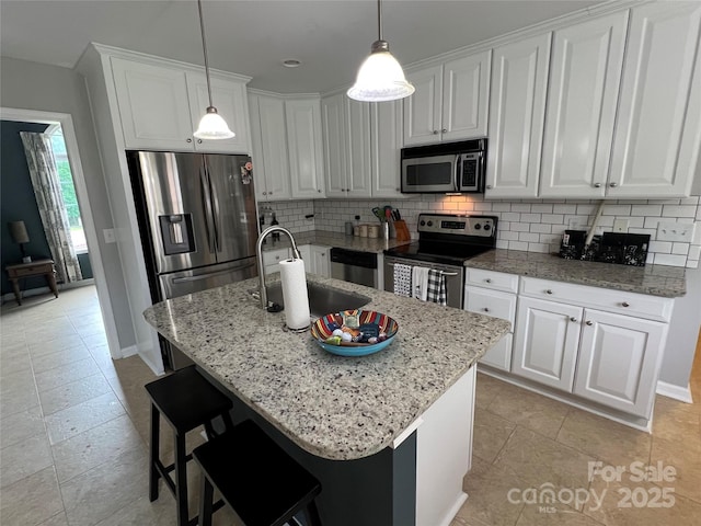 kitchen with stainless steel appliances, pendant lighting, white cabinets, decorative backsplash, and light stone counters
