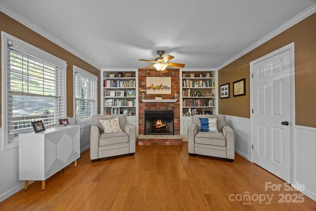 25 Alpine Way, Clyde, NC 28721 - sitting room featuring a fireplace, light wood-style flooring, ceiling fan, built in shelves, and wainscoting