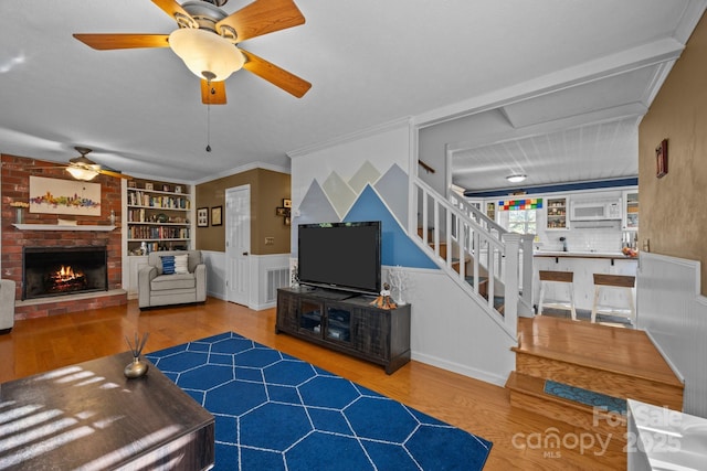 25 Alpine Way, Clyde, NC 28721 - living area featuring ceiling fan, wood finished floors, built in features, a fireplace, and wainscoting