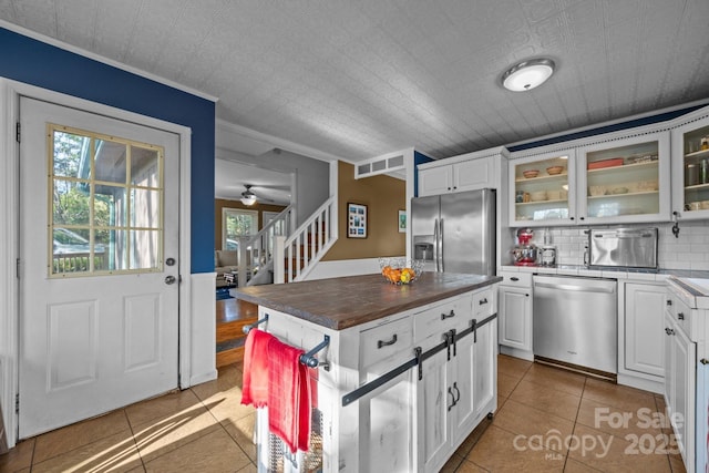 25 Alpine Way, Clyde, NC 28721 - kitchen featuring appliances with stainless steel finishes, tile patterned floors, glass insert cabinets, white cabinetry, and crown molding