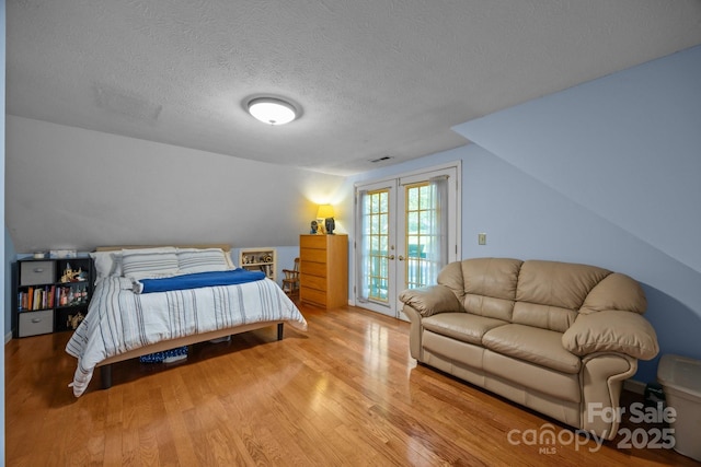 25 Alpine Way, Clyde, NC 28721 - bedroom with vaulted ceiling, wood finished floors, access to outside, french doors, and a textured ceiling