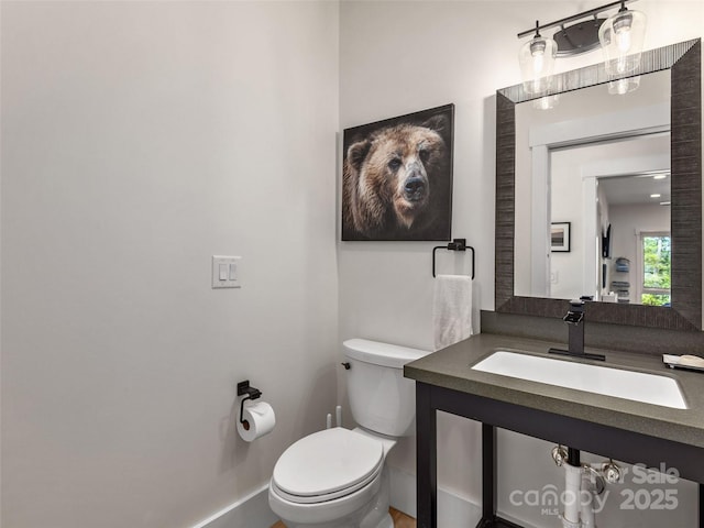 half bath featuring a sink, toilet, and baseboards