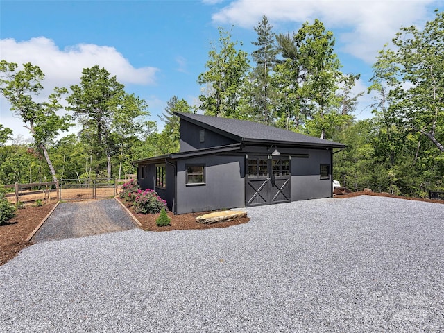 view of home's exterior with fence and gravel driveway