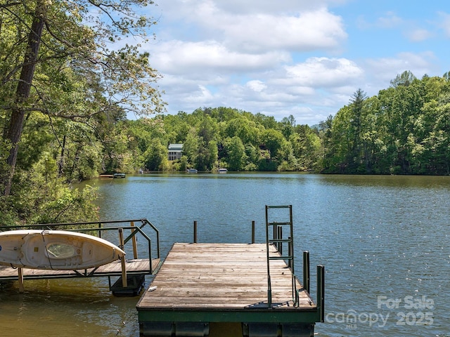 view of dock with a water view and a forest view