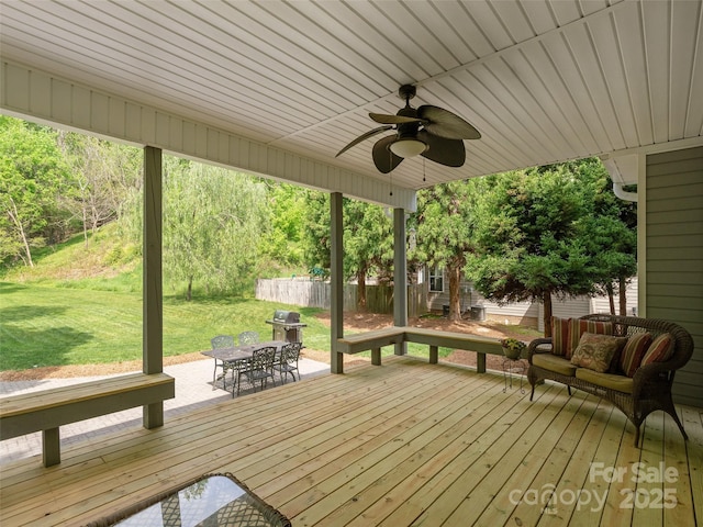 wooden terrace with fence, a patio area, a grill, a yard, and a ceiling fan
