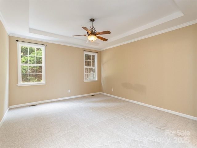 empty room featuring a ceiling fan, a raised ceiling, light carpet, and baseboards