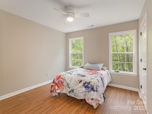 bedroom with light wood finished floors, baseboards, ceiling fan, and visible vents