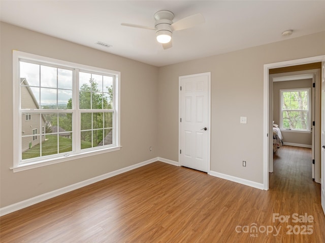 empty room with baseboards, ceiling fan, visible vents, and light wood-type flooring
