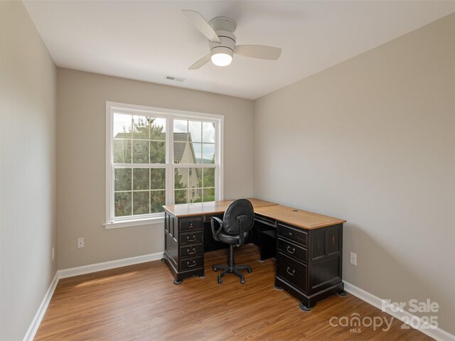 office space with baseboards, visible vents, and wood finished floors