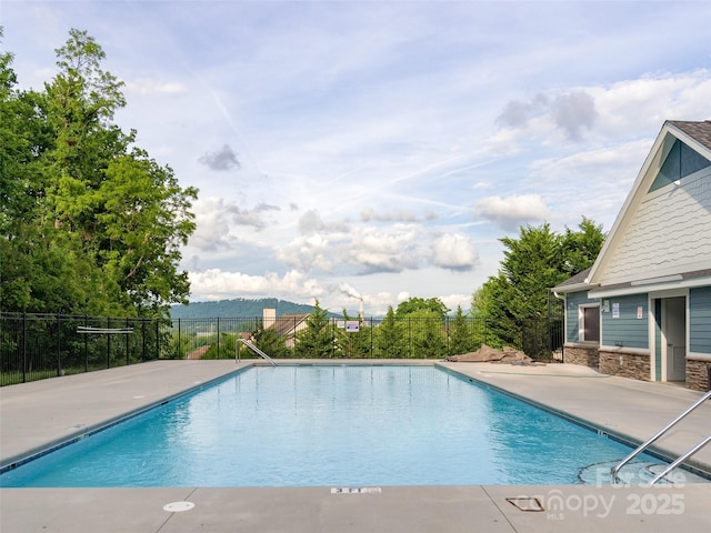 community pool with a patio area and fence