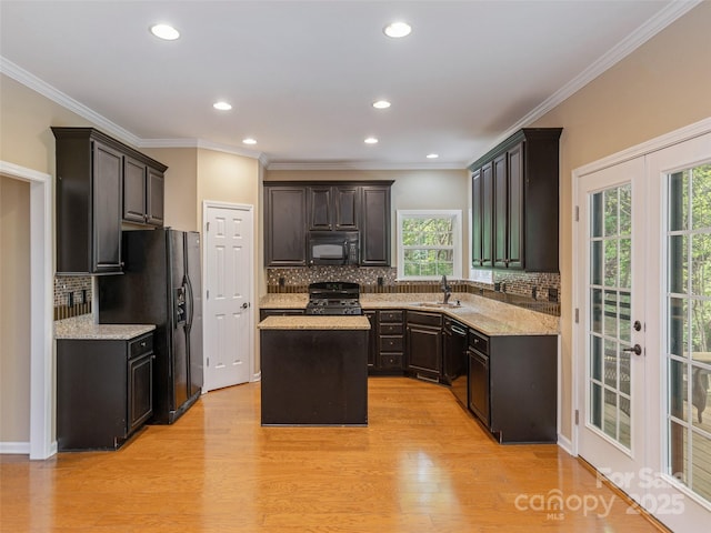 kitchen featuring a sink, french doors, black appliances, backsplash, and a center island
