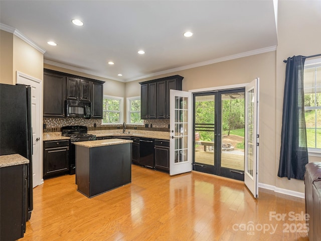 kitchen featuring a sink, black appliances, a kitchen island, tasteful backsplash, and radiator heating unit