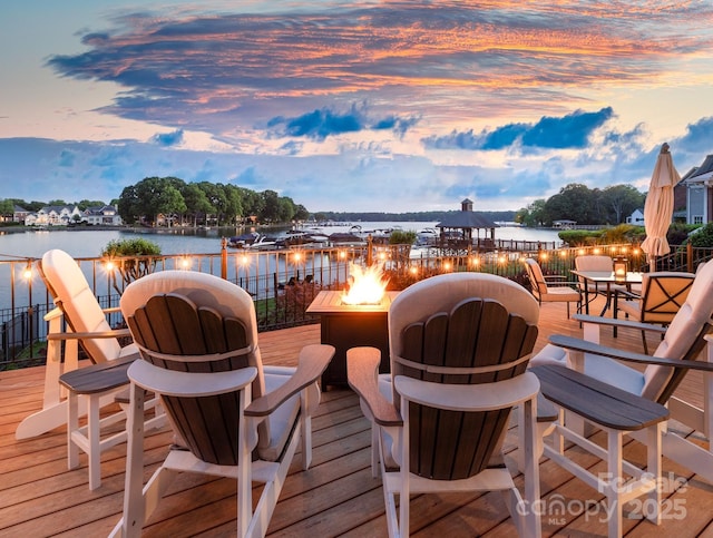 deck with an outdoor fire pit and a water view