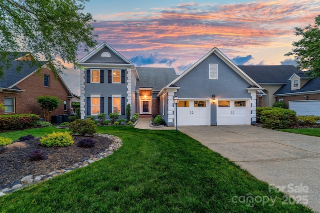 traditional-style house with a garage, driveway, stucco siding, and a lawn