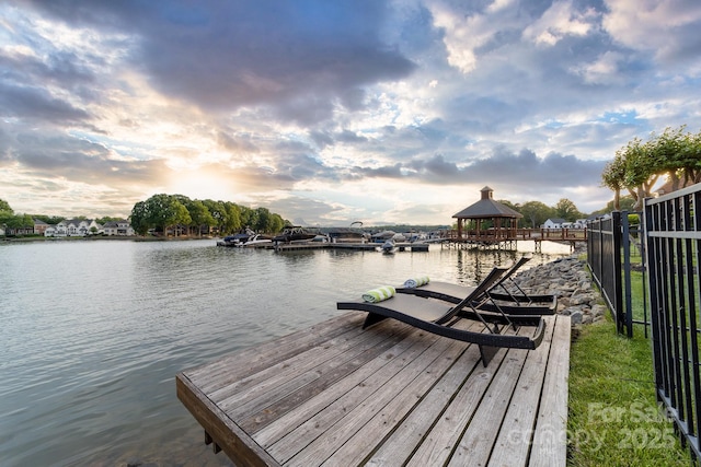 view of dock with a gazebo, fence, and a water view
