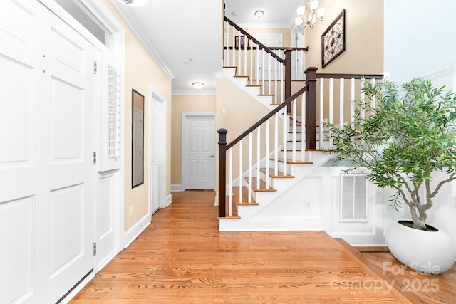 entryway featuring a notable chandelier, visible vents, stairs, crown molding, and light wood-type flooring
