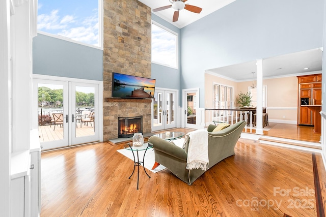 living room featuring french doors, a towering ceiling, crown molding, a wealth of natural light, and a ceiling fan