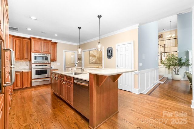 kitchen featuring light wood finished floors, a sink, stainless steel appliances, a warming drawer, and light countertops