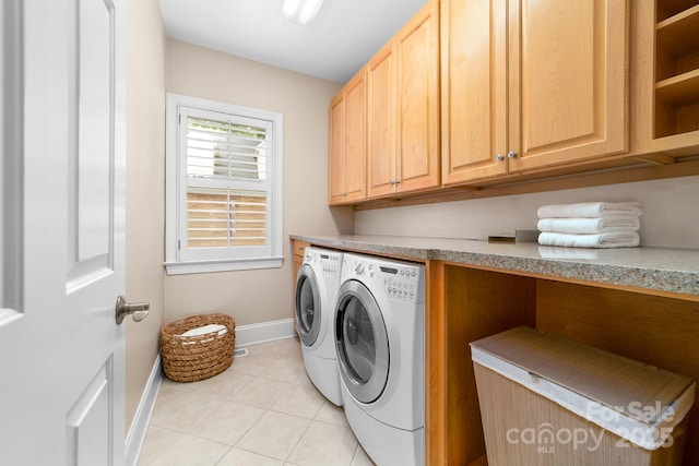 laundry room with washing machine and clothes dryer, baseboards, light tile patterned floors, and cabinet space