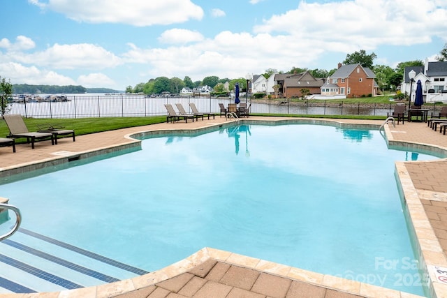 view of pool featuring fence, a water view, a fenced in pool, and a patio area