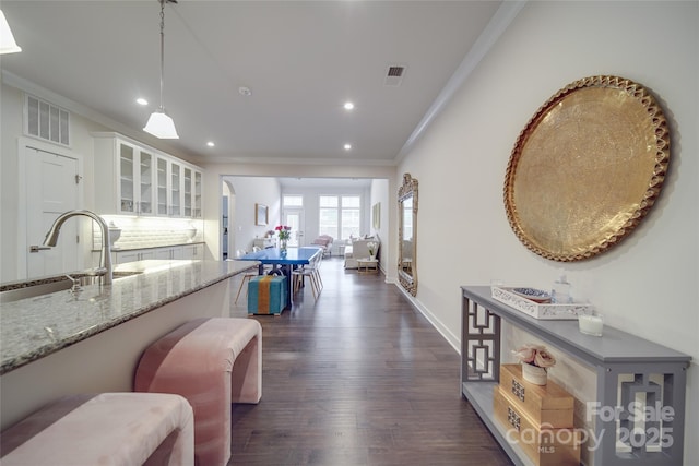corridor featuring crown molding, a sink, dark wood-style flooring, recessed lighting, and baseboards