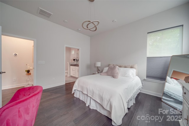 bedroom featuring wood finished floors, ensuite bath, and baseboards
