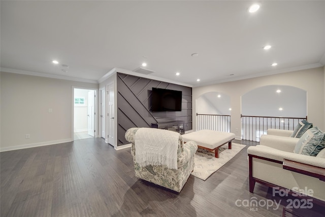 living room featuring ornamental molding, dark wood-type flooring, recessed lighting, baseboards, and arched walkways